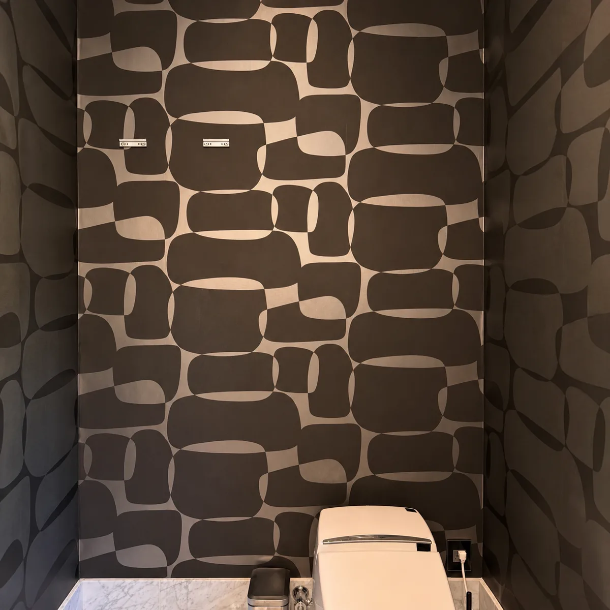 Powder room after installation of a dark metallic wallcovering with an organic pattern