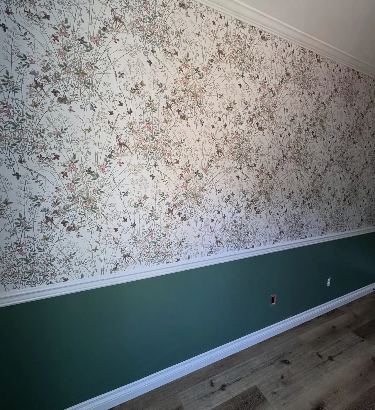 Nursery with fine floral wallpaper above a green painted wainscot