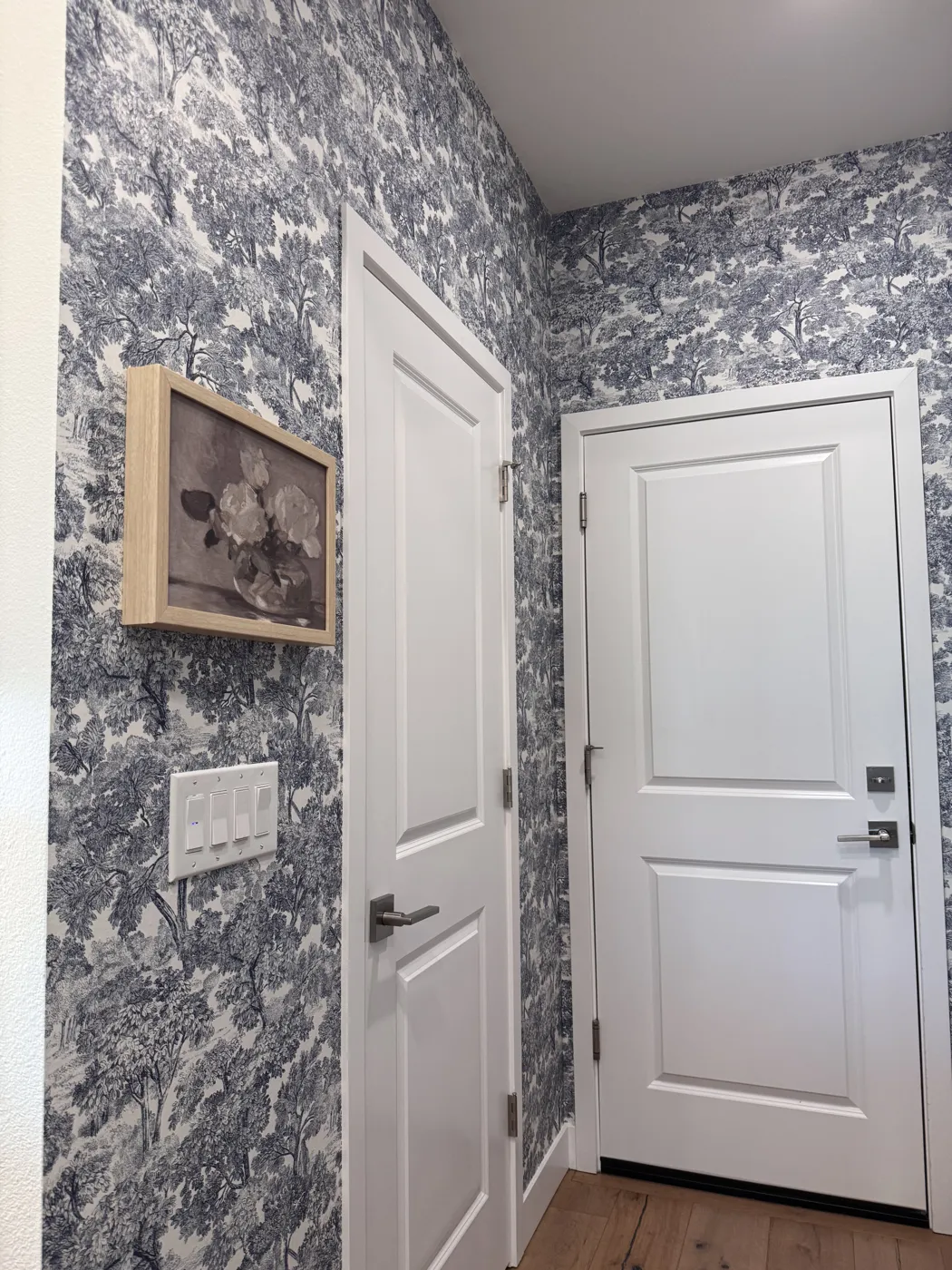 Blue toile wallpaper in an entry hallway around interior doors