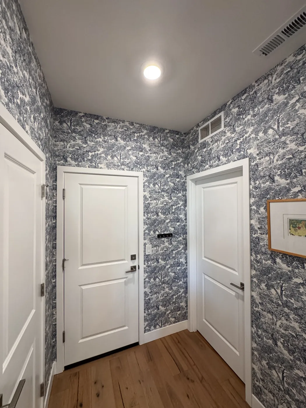Blue toile wallpaper in a mudroom with pattern matched at every corner