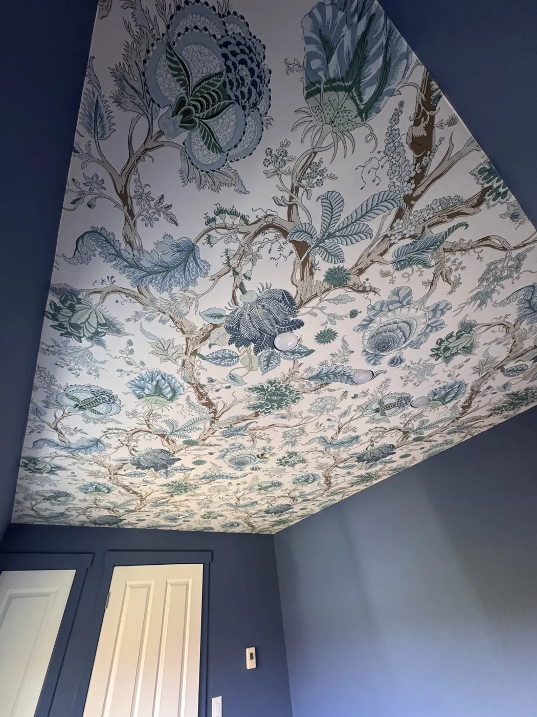 Blue floral wallpaper installed on a ceiling as a statement fifth wall