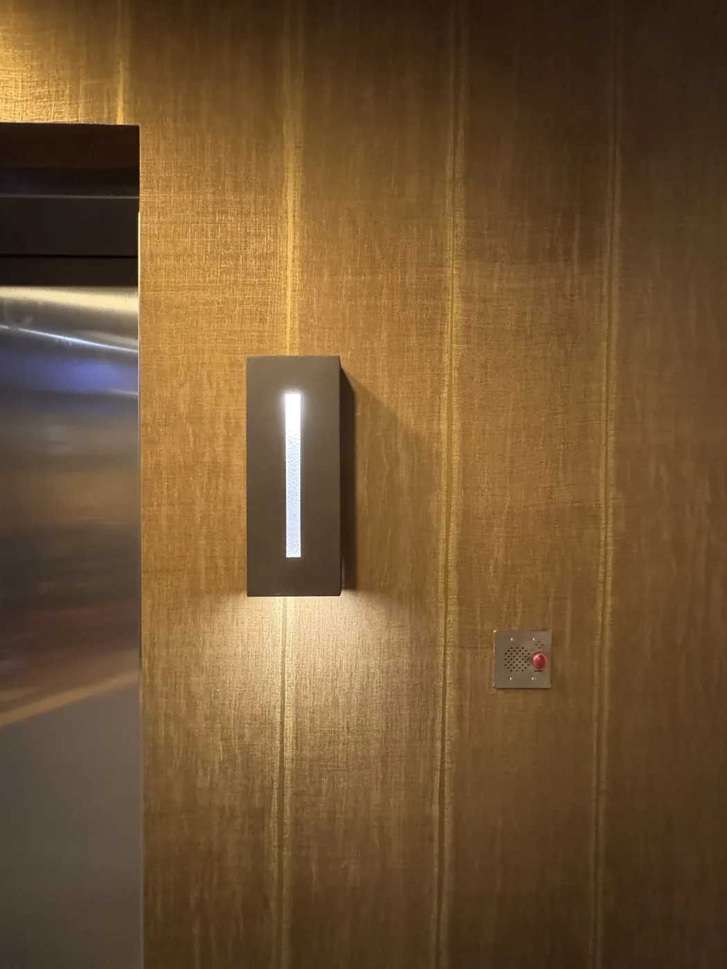 Detail of commercial wallcovering seams around a wall sconce and intercom