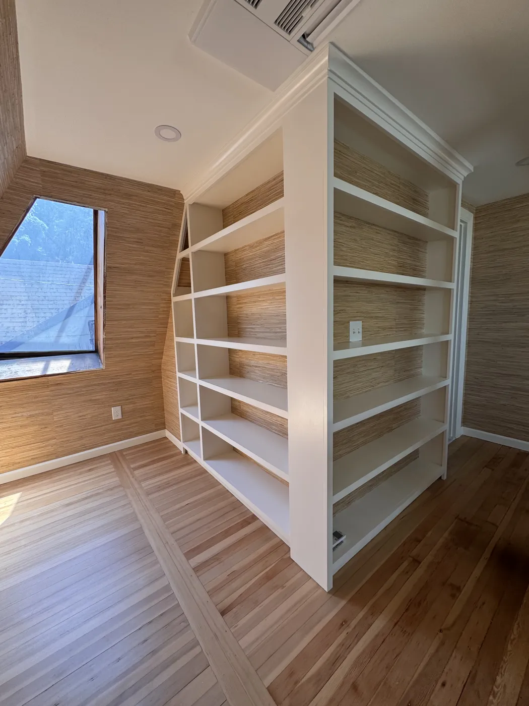Natural grasscloth wallpaper in an attic library with built-in shelves