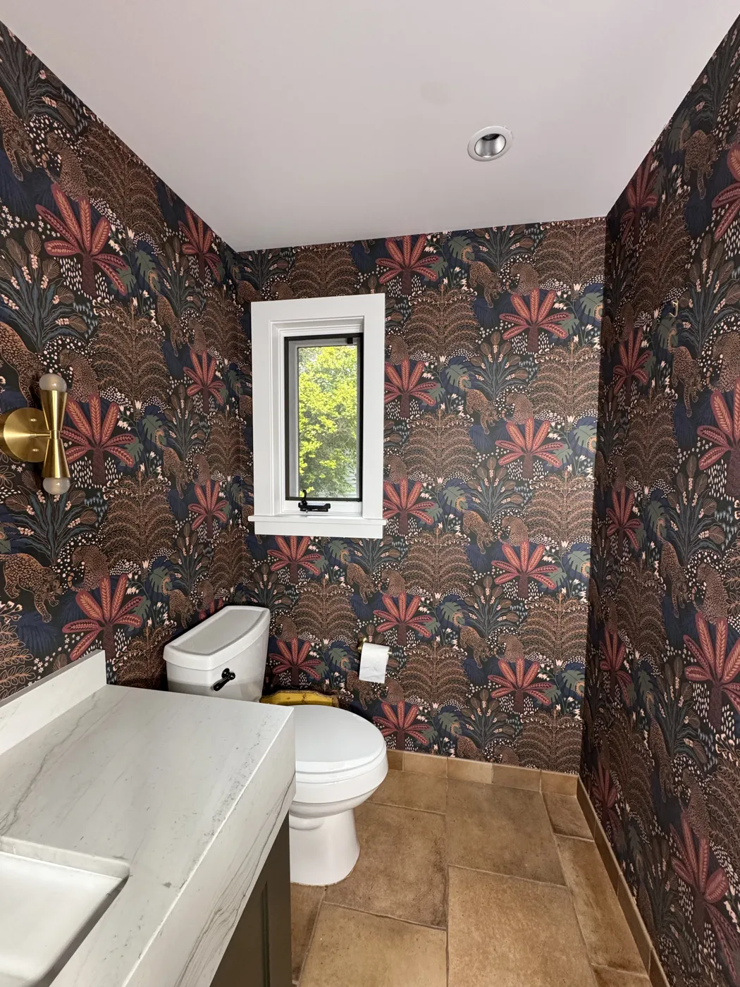 Dark jungle-print wallpaper matched around a powder room window