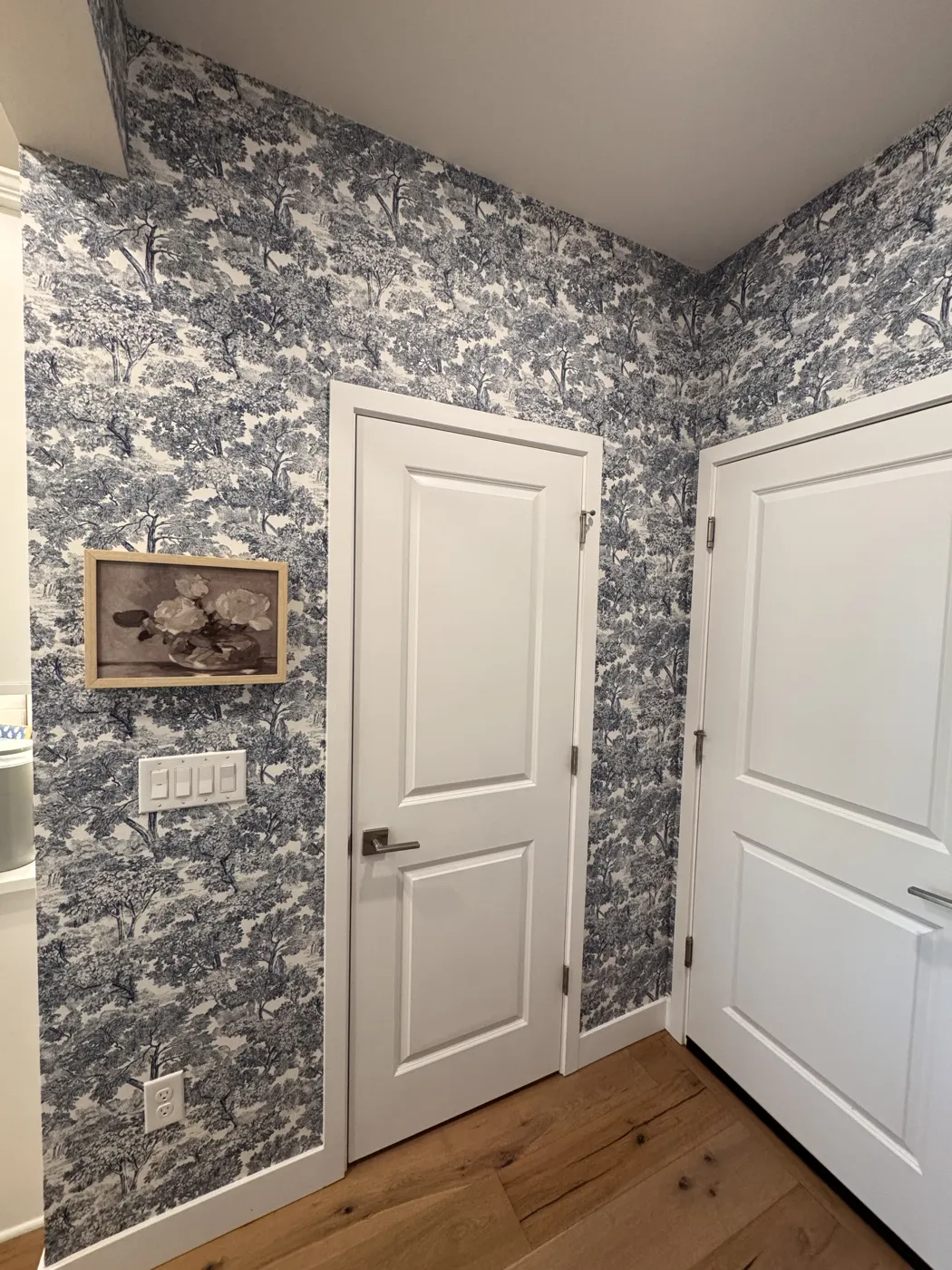 Toile tree-pattern wallpaper wrapping a hallway between two doors